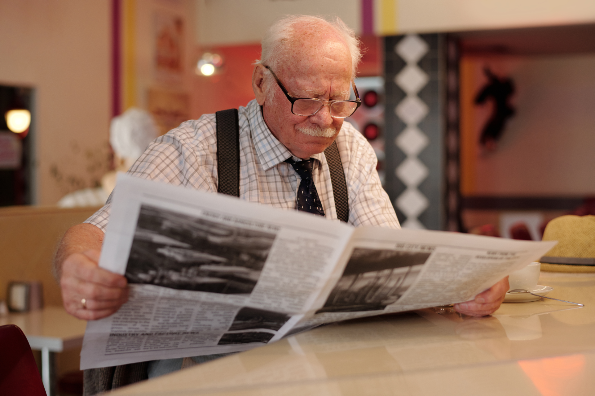 Une personne âgée qui lit le journal à la table d'un café